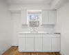 Kitchen with light countertops, light wood-type flooring, a sink, and white cabinets