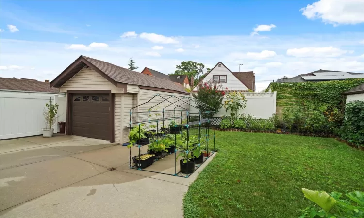 View of yard with concrete driveway, fence, a detached garage, and an outdoor structure