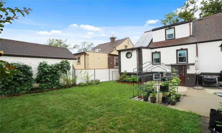 View of front of home featuring a shingled roof, fence, stucco siding, a front lawn, and a patio area