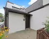 Doorway to property featuring a shingled roof, a patio area, roof mounted solar panels, and stucco siding