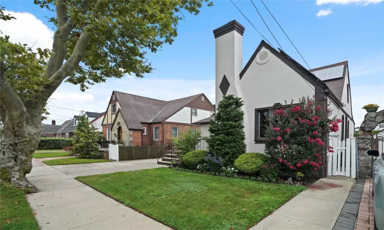 View of front of home featuring a front yard, fence, and stucco siding