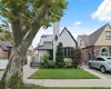 View of front of home with solar panels, stucco siding, a gate, fence, and a front yard