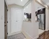 Kitchen with visible vents, vaulted ceiling, high end fridge, dark brown cabinets, and decorative backsplash