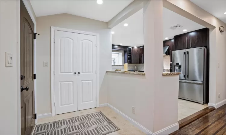 Kitchen with visible vents, vaulted ceiling, high end fridge, dark brown cabinets, and decorative backsplash