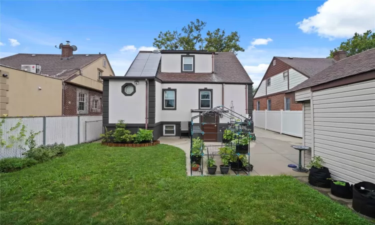 Back of house with a fenced backyard, roof with shingles, a lawn, stucco siding, and a patio area