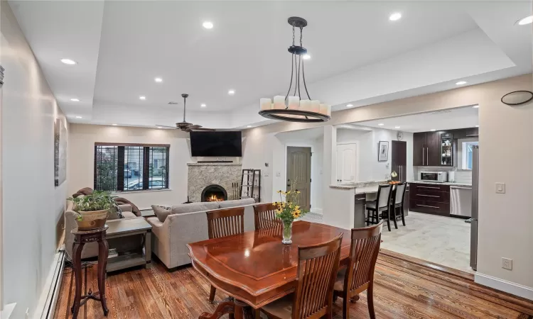 Dining area with a fireplace, wood finished floors, a ceiling fan, and recessed lighting