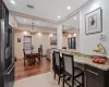 Kitchen featuring dark brown cabinetry, high end refrigerator, visible vents, light stone countertops, and a kitchen bar