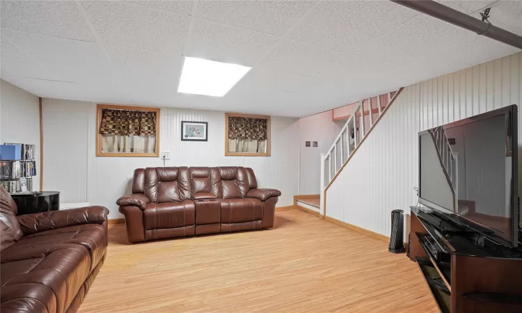 Living area featuring light wood-style floors, baseboards, and stairs