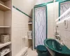 Bathroom with tile walls, tiled shower, toilet, tile patterned flooring, and a sink