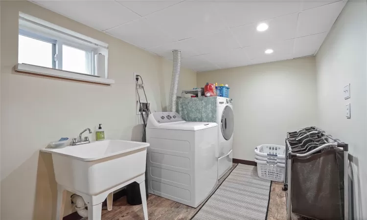 Clothes washing area with washer and dryer, recessed lighting, a sink, light wood-type flooring, and laundry area