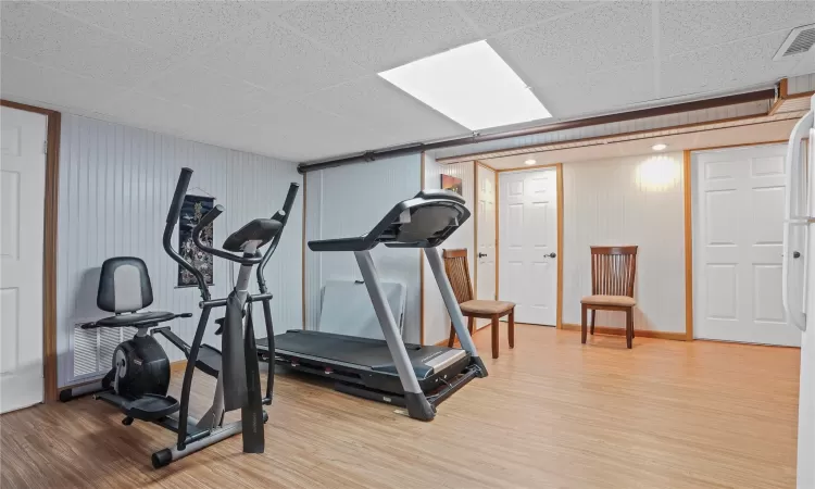 Exercise room featuring visible vents, baseboards, and wood finished floors