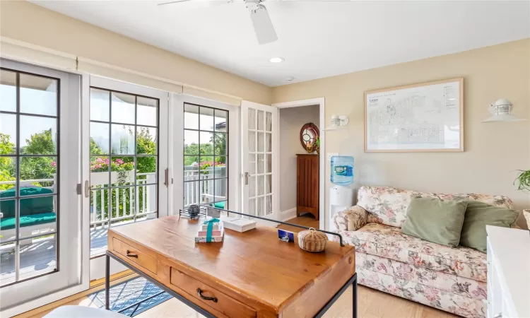 Home office featuring sliding glass doors, ceiling fan, and wood finished floors