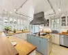 Kitchen with Antique Heart Pine countertops imported from a restored barn in Pennsylvania.  Tile backsplash,  stainless steel dishwasher, white cabinetry, and stainless steel exhaust range hood