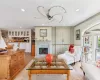 Living room with light wood-type flooring, crown molding, built in cabinets with television inside, and a tiled wood burning fireplace