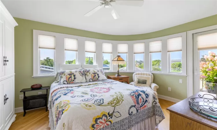 Bedroom 2, ensuite with access to exterior second floor deck, multiple windows, and hardwood floors