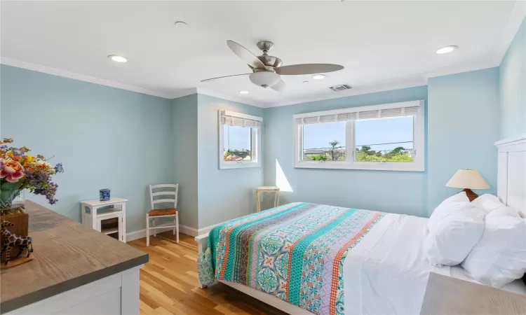 Bedroom 5 featuring natural light, wood flooring, and a ceiling fan with light