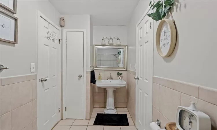 Full bathroom featuring wainscoting, tile walls, and tile patterned floors