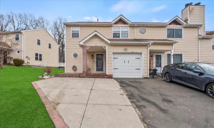 View of property featuring aphalt driveway and a front yard