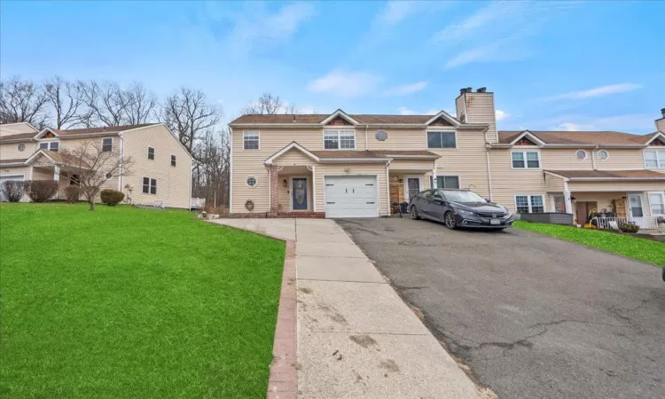 Multi unit property with aphalt driveway, a garage, and a front lawn