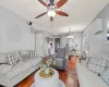 Living room featuring a baseboard heating unit, ceiling fan with notable chandelier, and dark wood finished floors