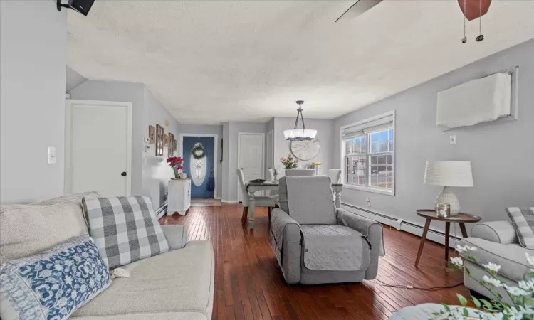 Living room featuring baseboards, a textured ceiling, a chandelier, and hardwood / wood-style floors