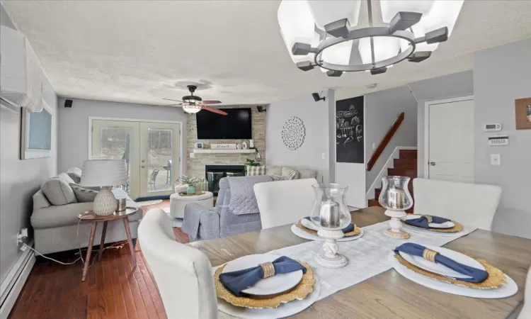 Dining area with ceiling fan, a textured ceiling, dark wood-type flooring, stairs, and baseboard heating