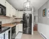 Kitchen featuring a textured ceiling, light tile patterned flooring, a baseboard heating unit, a sink, and black appliances