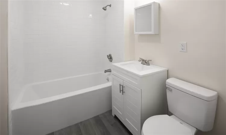 Bathroom featuring vanity, bathing tub / shower combination, wood finished floors, and toilet