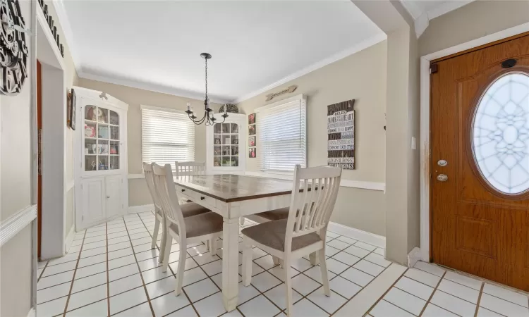 Dining area featuring crown molding, an inviting chandelier, and light tile patterned floors