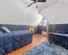 Bedroom with radiator, ceiling fan, wood finished floors, vaulted ceiling, and wood walls