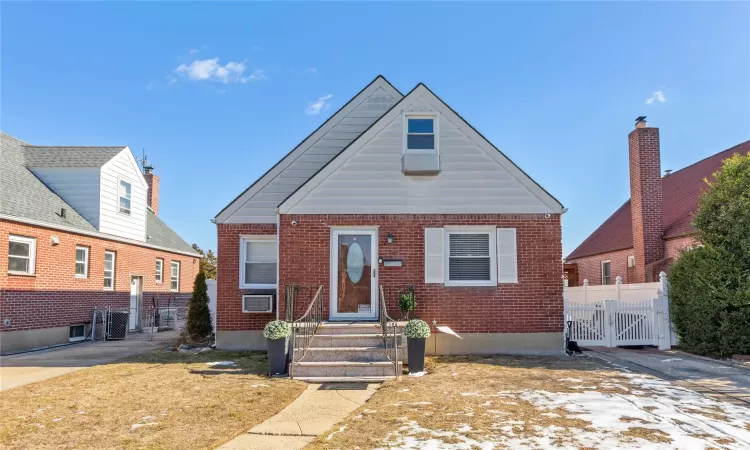 View of front of property featuring brick siding, fence, and a gate