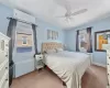 Bedroom with a wall unit AC, ceiling fan, baseboards, and light colored carpet