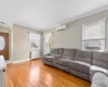 Living area featuring ornamental molding, baseboards, a wall mounted air conditioner, and light wood finished floors