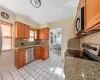 Kitchen with light stone counters, stainless steel appliances, visible vents, brown cabinetry, and a sink