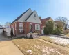 View of front of house with brick siding, a chimney, fence, and a gate