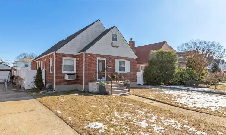 View of front of house with brick siding, a chimney, fence, and a gate