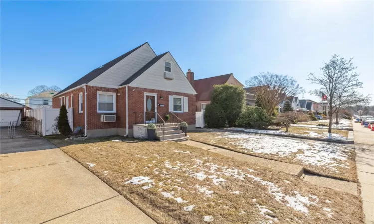 Bungalow featuring a gate, brick siding, and fence