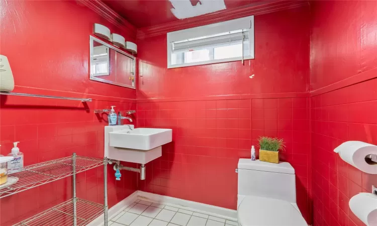 Half bath featuring toilet, tile walls, crown molding, and tile patterned floors