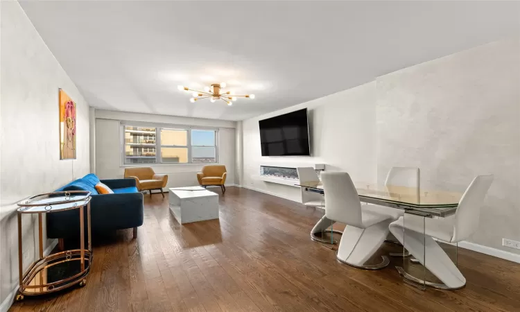 Living area featuring dark wood-style floors, a chandelier, and baseboards