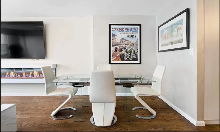 Office featuring a glass covered fireplace, baseboards, and wood finished floors