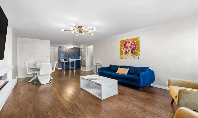 Living room featuring dark wood-style floors, a chandelier, and baseboards