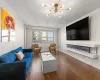 Living area with baseboards, dark wood-style flooring, a glass covered fireplace, and an inviting chandelier