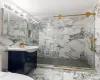 Bathroom with toilet, a marble finish shower, and vanity