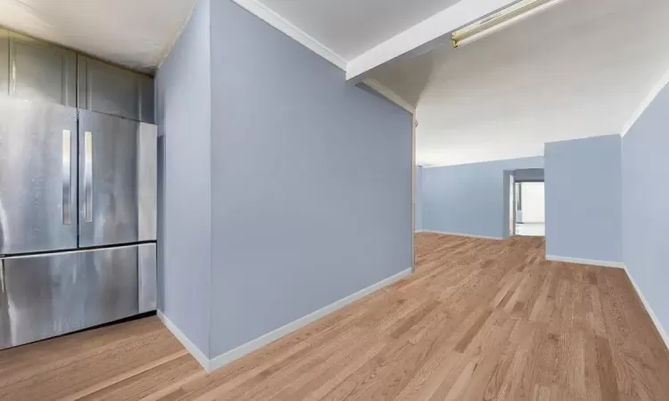 Corridor with ornamental molding, light wood-type flooring, and baseboards