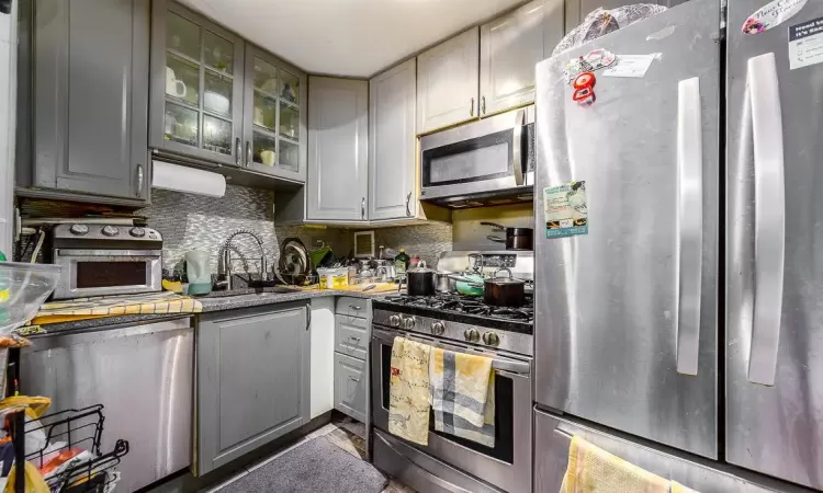 Kitchen with stainless steel appliances, tasteful backsplash, a sink, and glass insert cabinets