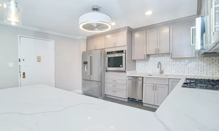 Kitchen featuring backsplash, crown molding, stainless steel appliances, and a sink