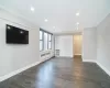 Unfurnished living room featuring recessed lighting, baseboards, ornamental molding, radiator heating unit, and dark wood finished floors