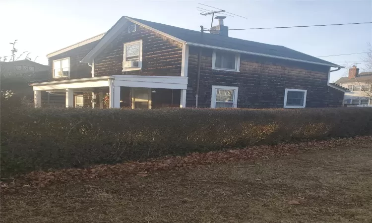 View of side of home with cooling unit and a chimney