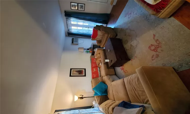 Living room with an AC wall unit, wood finished floors, and french doors