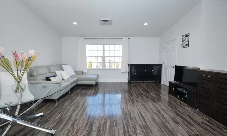 Living room with recessed lighting, visible vents, vaulted ceiling, and wood finished floors